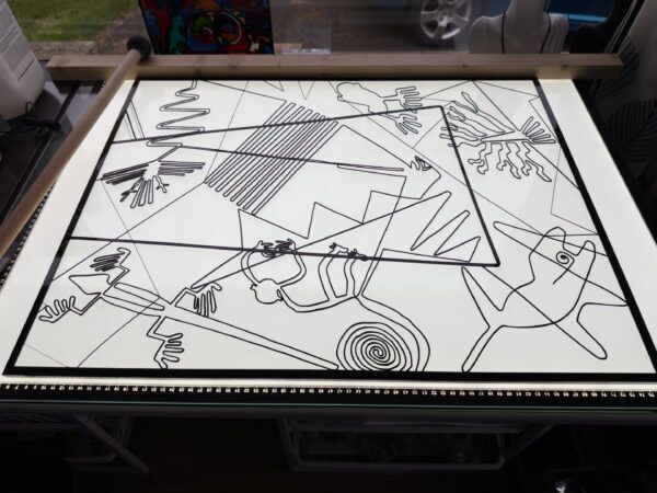 Bottom half of the stained glass design cut out of black plastic - glued to clear cast acrylic sheet - on light table ready to be painted